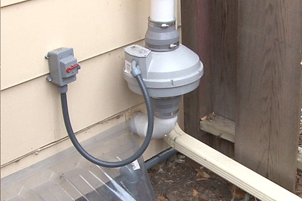 Exterior radon mitigation fan and vent pipe installed at a Eau Claire County home